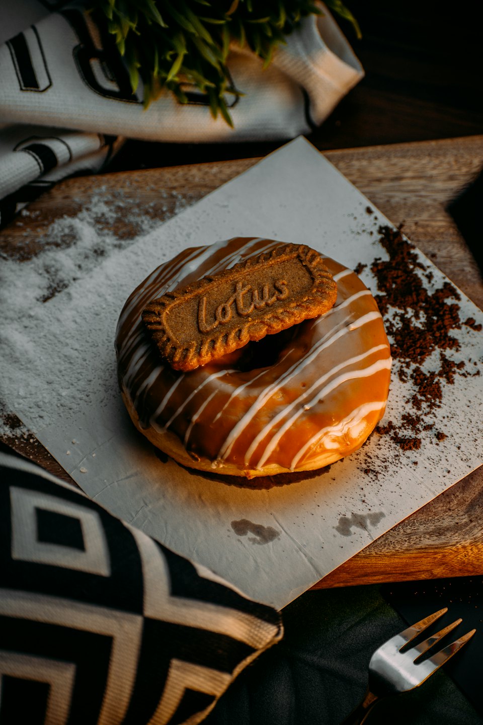 A donut with caramel icing and a cookie topping sits on parchment paper.