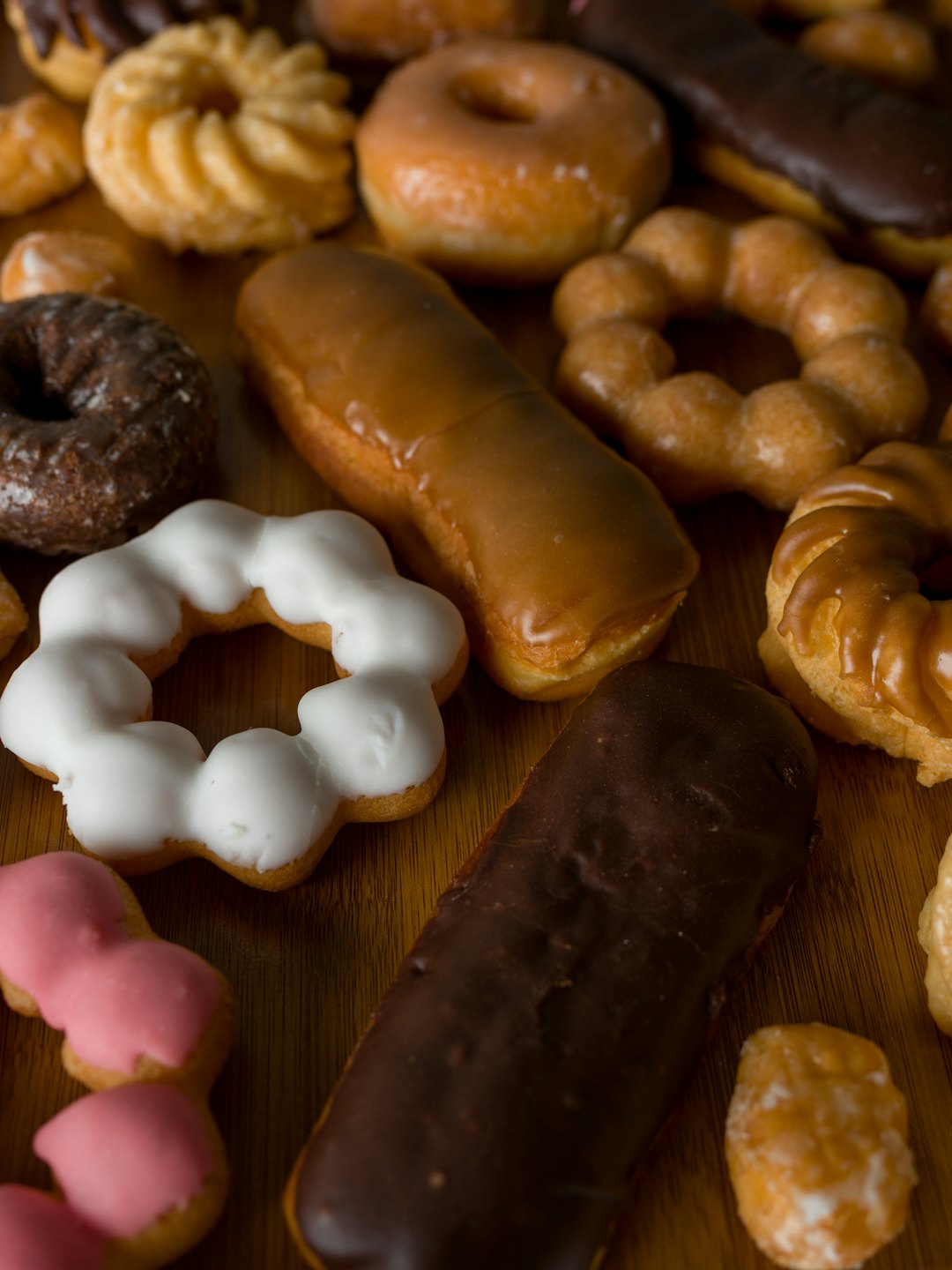 Assorted fresh donuts and pastries arranged on a wooden table.