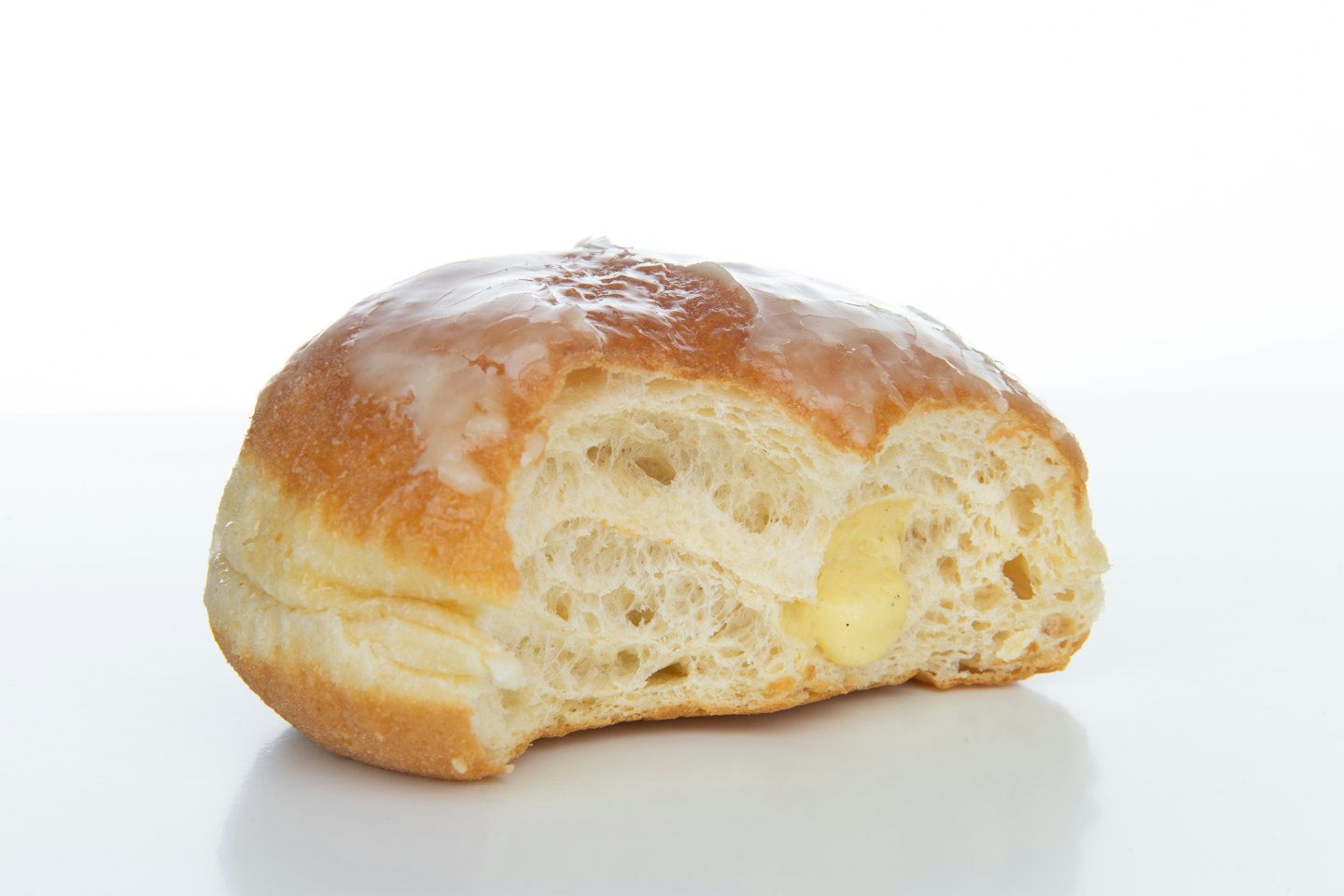 A glazed cream-filled donut with a bite taken out.