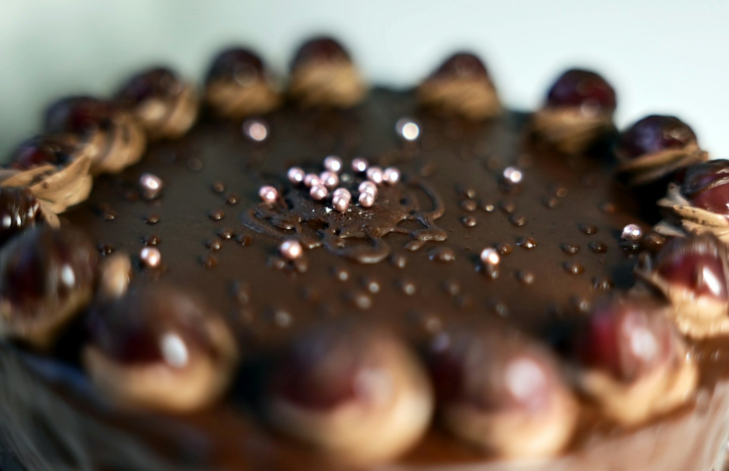Chocolate cake topped with cream dollops, cherries, and edible pearls.