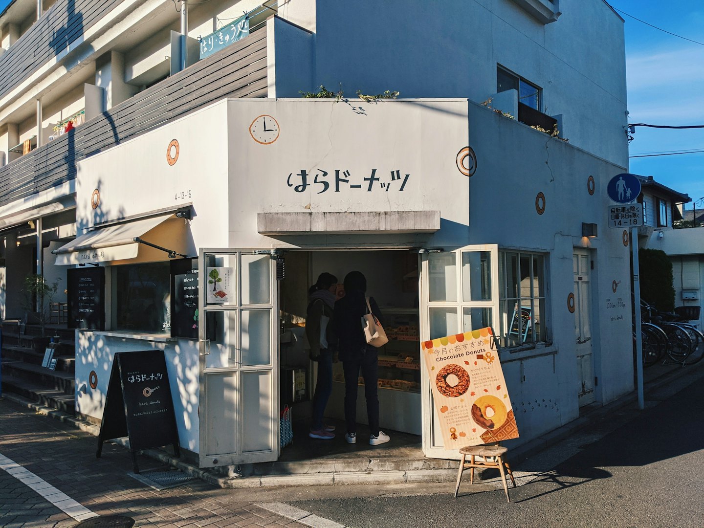 Customers stand at the entrance of a Japanese donut shop.